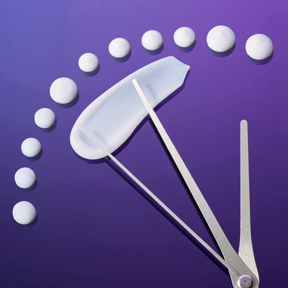 Tweezers holding a cotton pad with white cotton balls arranged in a circle on a purple background
