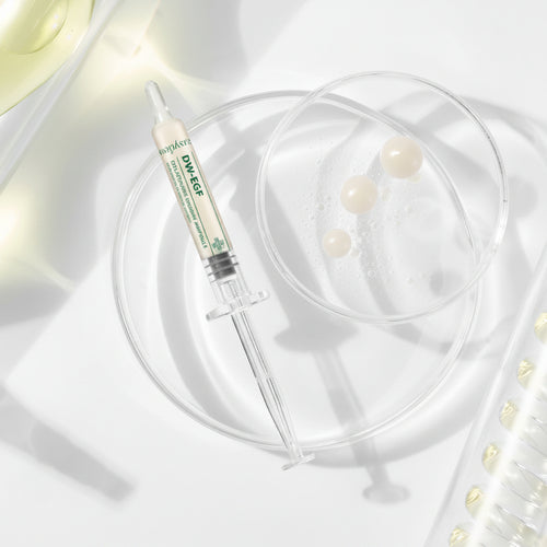 Skincare product with syringe and pearls on a soft white background