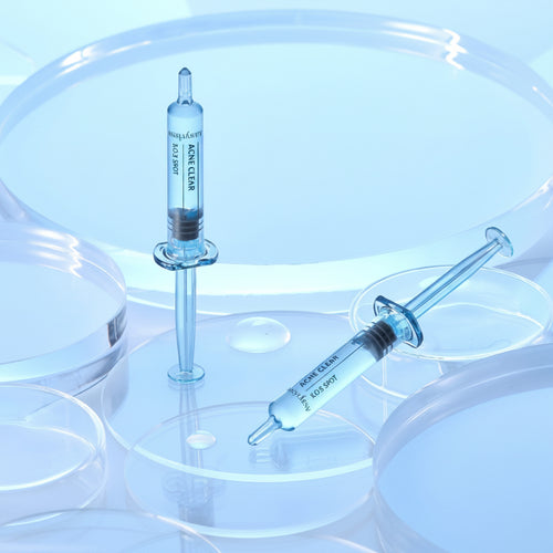 Two syringes with clear liquid on a reflective surface